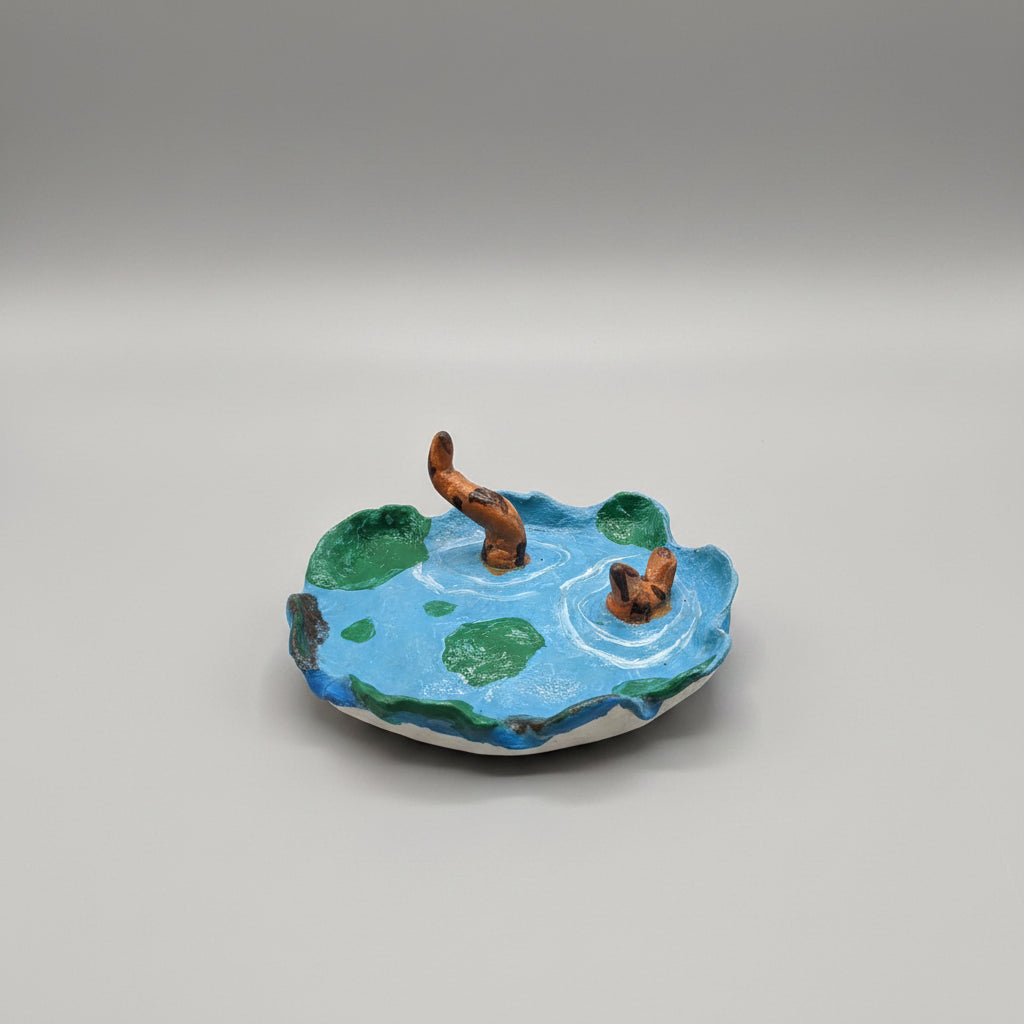 A small handmade globe model with blue oceans, green landmasses, and brown continents, resting on a black and beige patterned pillow.