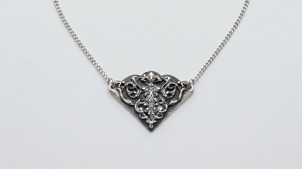 A silver filigree pendant necklace with a triangular pendant, displayed on a textured brown leather surface.