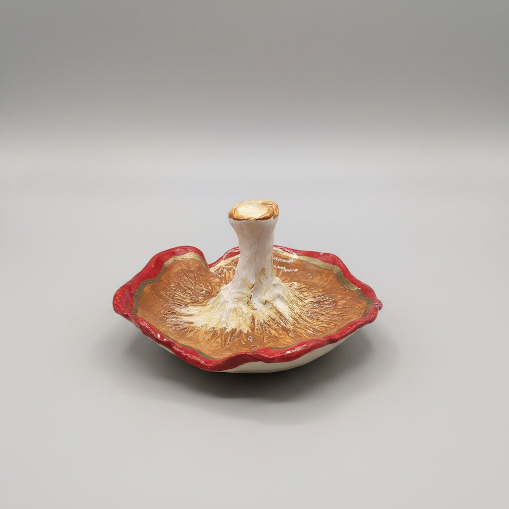 A red mushroom-shaped decorative object with white spots and black outlines, resting on a patterned cushion in a home interior setting.